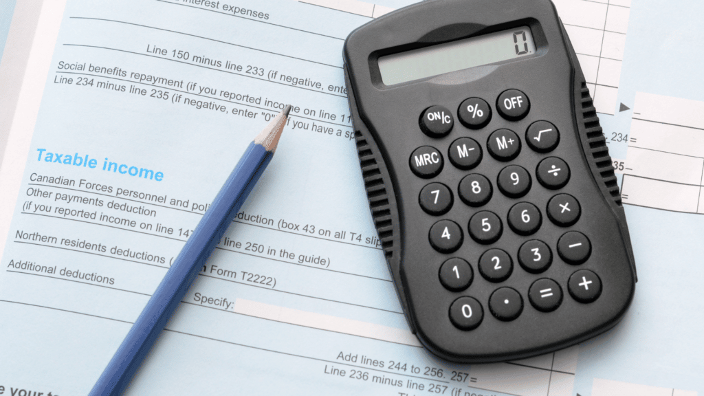 An image of Canadian Income Tax forms with a pencil and calculator on top of the forms.
